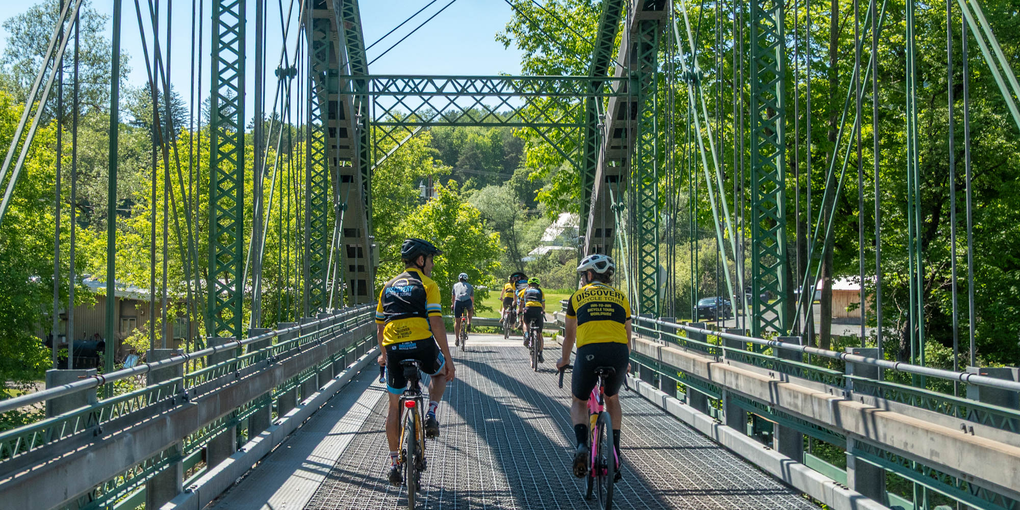 Discovery cyclists biking across bridge in Vermont